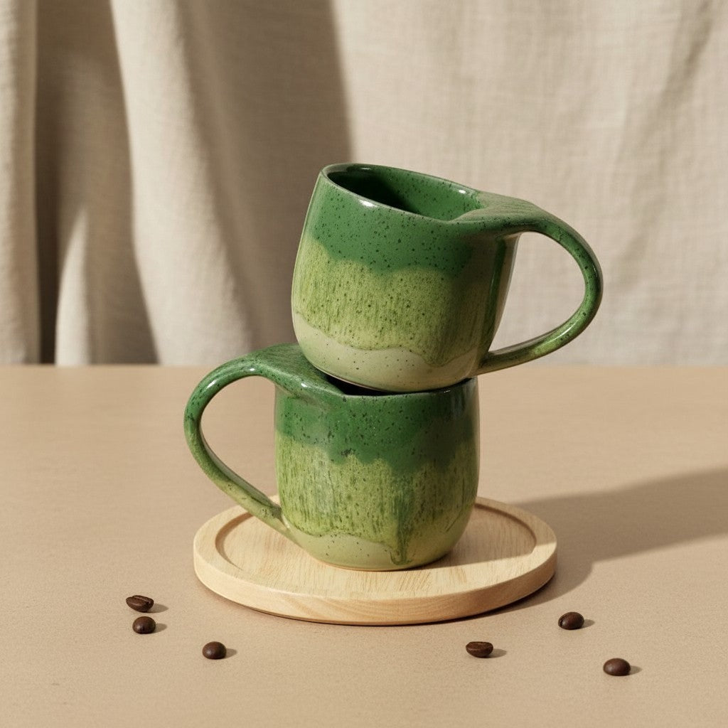 Two stacked textured green tide mermaid mugs with handles, resting on a wooden coaster. Eternal Pottery.