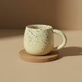 Eternal Pottery speckled cream ceramic mug with rounded handle, perfect for coffee or tea.