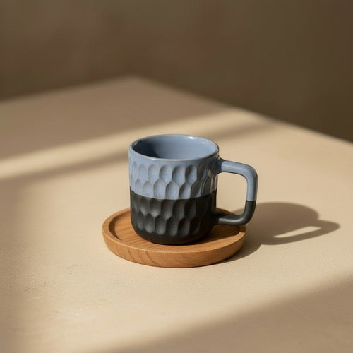 Eternal Pottery two-tone blue and charcoal ceramic mug with geometric texture, on a wooden coaster.