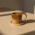 Eternal Pottery textured caramel mermaid mug with handle on a wooden coaster.