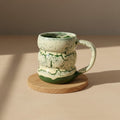 Eternal Pottery textured green marble triple bubble mug with handle on a wooden coaster.
