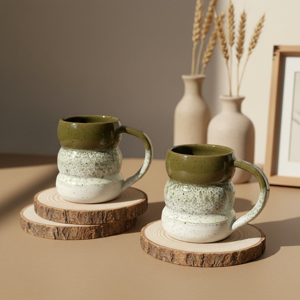 Two textured olive mist triple bubble mugs with handles resting on wooden coasters, rustic design. Eternal Pottery.