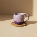 Eternal Pottery textured pink sand mermaid mug with handle on a wooden coaster.