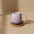 Eternal Pottery pink sand round mug resting on wooden coaster.
