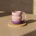 Eternal Pottery textured pink sand triple bubble mug with handle on a wooden coaster.