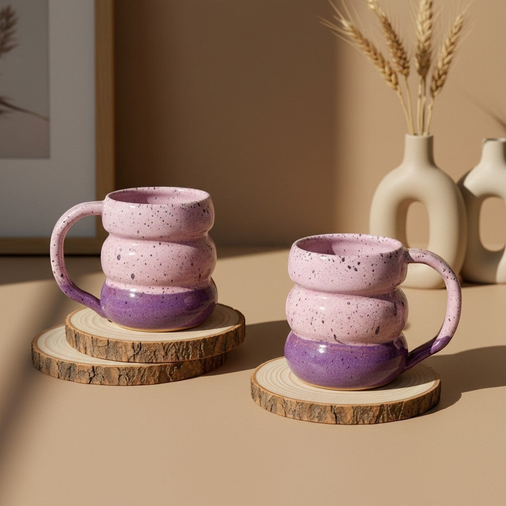 Two textured pink sand triple bubble mugs with handles resting on wooden coasters, rustic design. Eternal Pottery.
